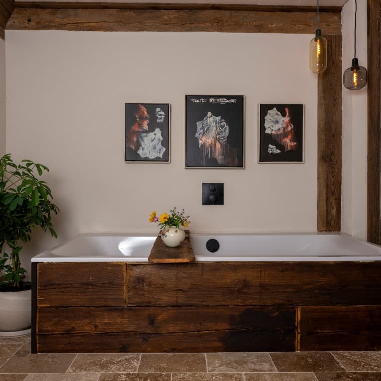 Die Tawa Badewanne mit einer Verkleidung aus alten Eichenbalken als Herzstück des Bades. Die Kunst an den Wänden von Jörg Heikhaus unterstreicht das Ambiente. Die Tawa Badewanne mit einer Verkleidung aus alten Eichenbalken als Herzstück des Bades. Die Kunst an den Wänden von Jörg Heikhaus unterstreicht das Ambiente.